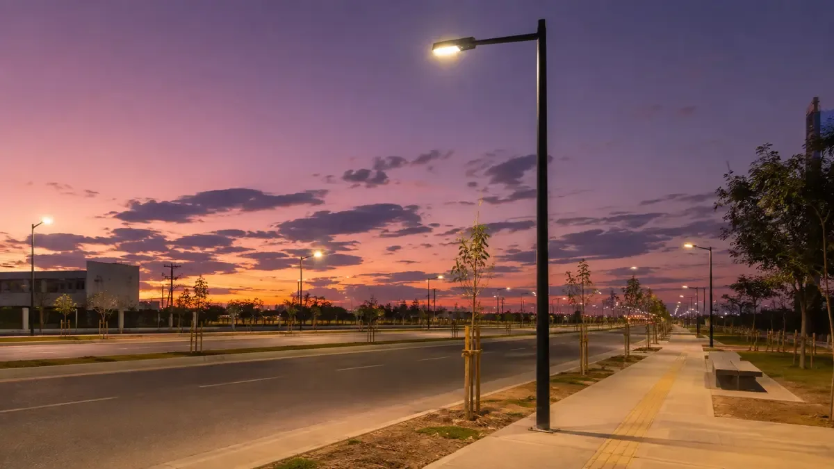 Columna de alumbrado LED encendida en una avenida al atardecer